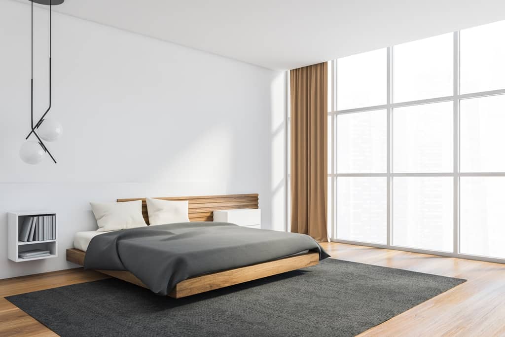 style bedroom with white and wooden walls, rug under the bed and large windows